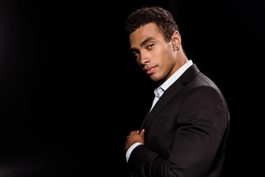 handsome bi-racial man looking at camera isolated on black