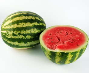 half ripe watermelon with red juicy pulp and seeds and a whole green