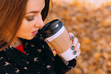 Obraz premium young woman drinking coffee in the park. close up. woman with fr