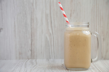 Tasty peanut butter banana smoothie in a glass jar mug, side view. Close-up. Space for text.