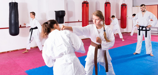 Kids in kimonos exercising techniques in pair during taekwondo class at gym