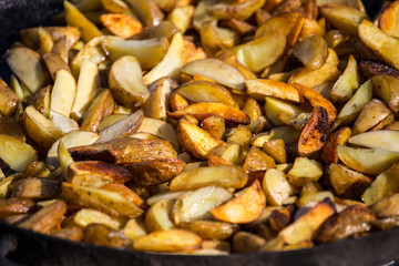 Roast potatoes in a large pan. Delicious food at the festival. Many potatoes on the table in a metal tray.