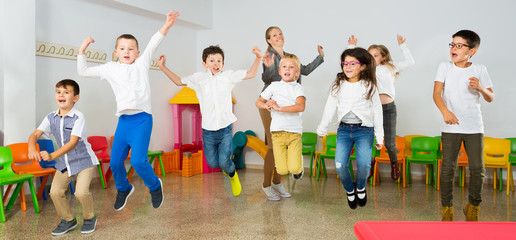 Obraz premium Children with teacher jumping together in schoolroom