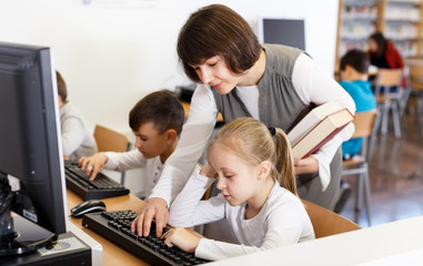 Fototapeta na wymiar Woman teacher helping tween girl in computer class