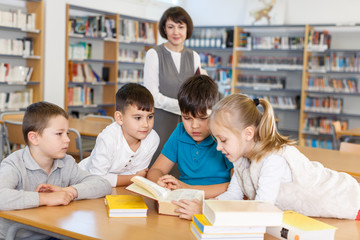 Female librarian and schoolkids during classes in library