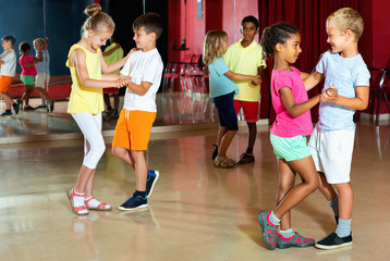 Group of positive childrens trying dancing with partner in classroom