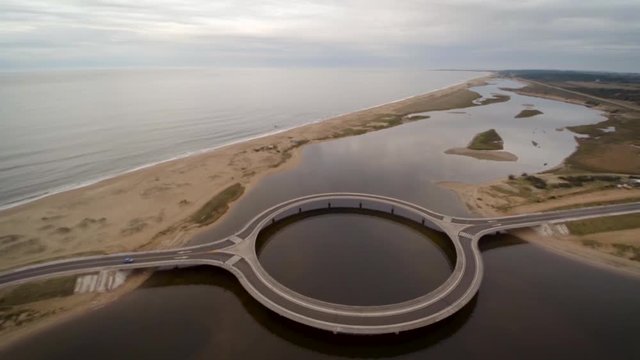 A drone shot over Puente Laguna Garzon, Cuba, on a cloudy day. The drone flies out to reveal the sea and lagoon which stretches into the horizon.