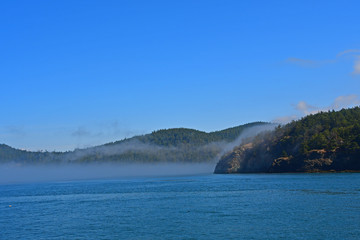 Morning fog hugs the coast of Deception Pass as it enters the Salish Sea in Washington State