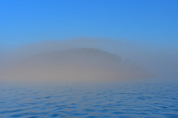 Morning fog hugs the coast of Deception Pass as it enters the Salish Sea in Washington State