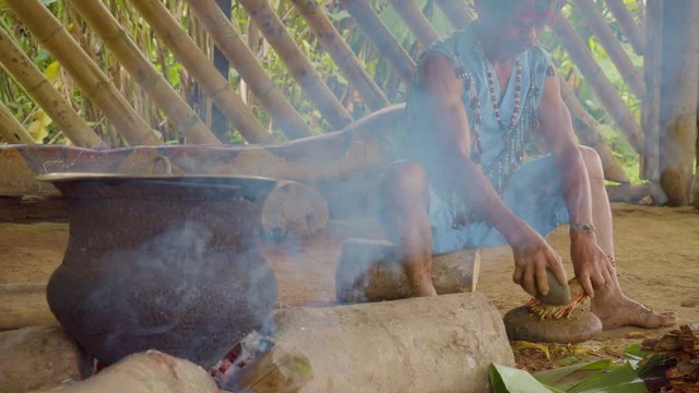 Indigenous Man Crushing Ayahuasca Sticks To Prepare Traditional Drink In Ecuador