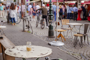 Selected focus at the outdoor vintage furniture of cafe or coffee shop located at old town square with blur background crowd of tourists in Düsseldorf, Germany. 