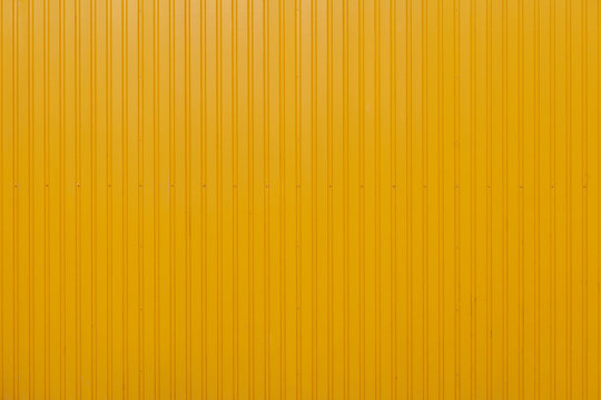 Yellow metal sheet panel or cladding with vertical line wave pattern.