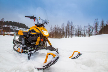 Yellow snowmobile closeup. ATV in the background of a winter landscape. Sale of snowmobiles. Winter...