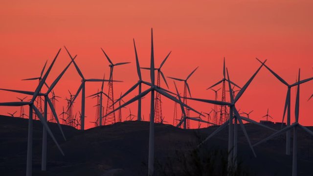 Row of Wind Turbines on mountain top at dawn