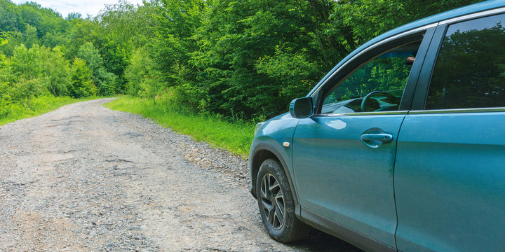 suv on the old forest road. cyan blue vehicle parked on the cracked asphalt way uphill among trees. view from the drivers door and side mirror. lost direction or navigation concept. abandoned car