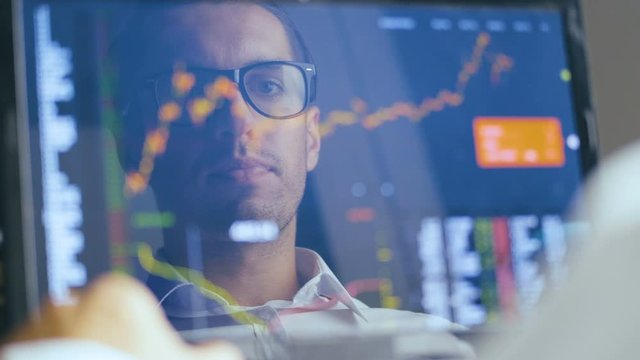 Double exposure: Man in Eyeglasses Working at Laptop and checks stock market. Reflection in the Monitor: Successful Businessman Working on a Laptop in office and Drinking Tasty Coffee.