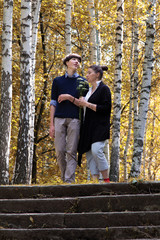 A middle-aged woman walks through the autumn forest with a teenager. Mother and son are standing on the stone steps. Family resting together on the weekend.