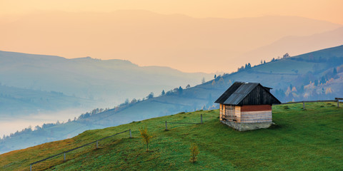 amazing beautiful rural area at dawn. morning in the carpathian mountains. fog in the distant valley. woodshed on the hill