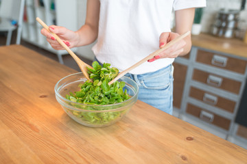 close up go female hands while cooking salad, stirs salad with spoons. Healthy food. vegetable salad. Diet. Healthy lifestyle. cooking at home.