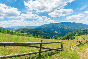Fototapeta na wymiar wonderful landscape of rural area at noon. amazing cloudscape above the distant mountain ridge. beautiful sunny weather. wooden fence on the grassy meadow