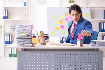Young male handsome employee in conflicting priorities concept