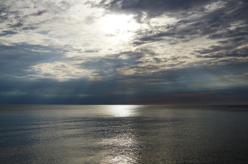 Dark sunset. The sun's rays shine over the surface of the lake