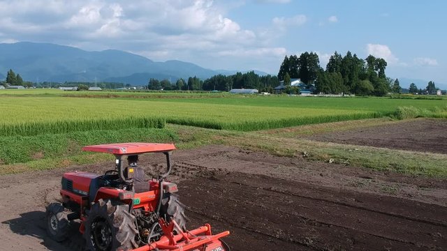 トラクターで農地を耕す日本人の男性　農業