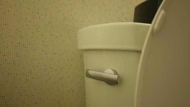Man pushes a toilet flush in modern bathroom