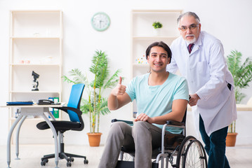Fototapeta premium Male patient in wheel-chair visiting old doctor