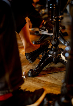 Closeup Legs Of A Man And A Woman Under The Table At Coffee Shop. Vintage Style Table In Restaurant. People Chill Out At The Coffe Shop On Holiday. Customer Sitting In Coffee House. Counter Bar.