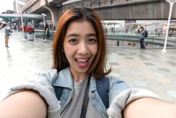 Young attractive Asian woman tourist taking a photo of selfie in urban city.