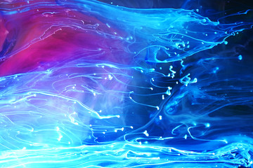 Blue and purple paints and inks swirling together in water abstract background