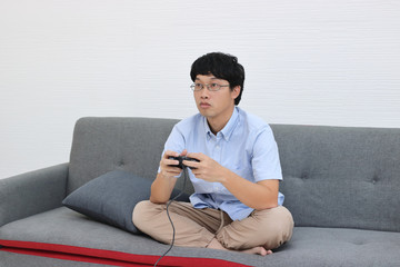 Young Asian man play game with joystick in living room.