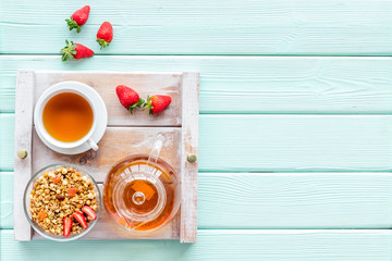 Breakfast on the tray with granola, tea and fruit on mint green wooden background top view mockup