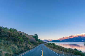 Long asphalt road landscape with mountain views and lake