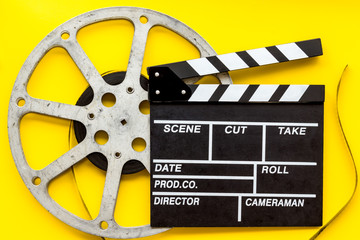 Movie premiere concept with clapperboard, film type on yellow background top view