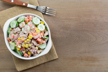 top view of tuna and vegetables salad in a ceramic bowl on wooden table, copy space. homemade style food concept.