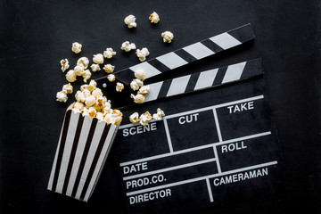Filmmaker profession with clapperboard and popcorn on black background top view
