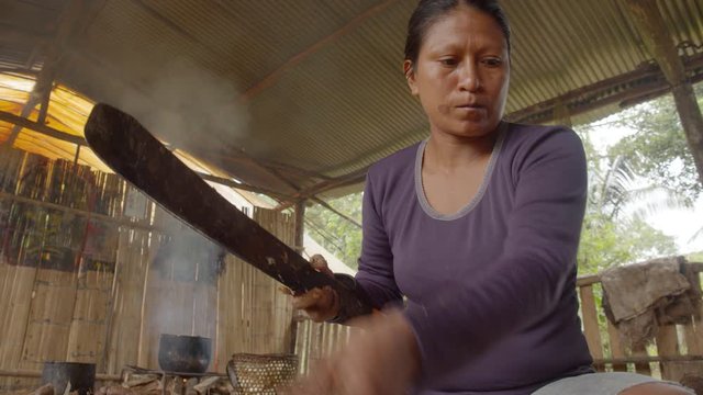 Indigenous Woman Peeling Yucca For Chicha Preparation In Ecuador
