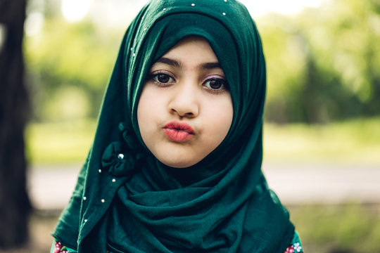 Portrait Of Happy Little Muslim Girls Child With Hijab Dress Smiling And Looking At Camera In The Park