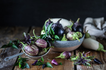 Eggplants of different colors and different grades on a wooden table.