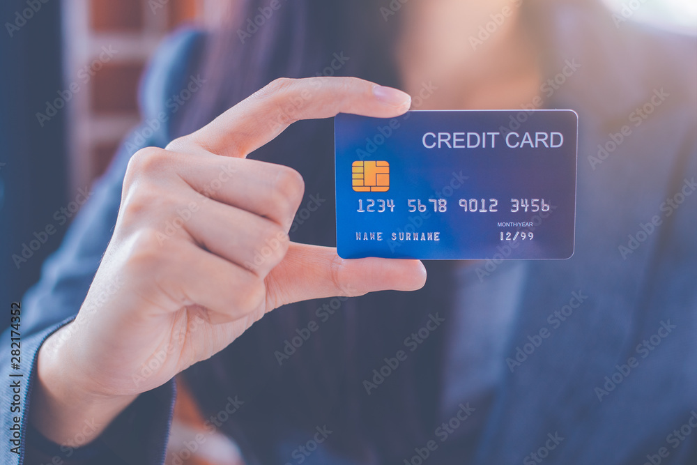 Wall mural Business women hand are showing a blue credit card.