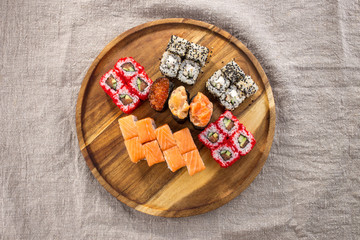 Japanese food restaurant sushi maki roll set on wooden round board on fabric grey background