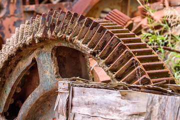 Large abandoned machine cogs are left to rust and decay in a junkyard.