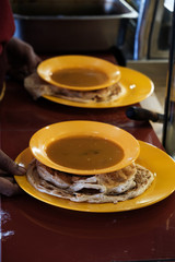 Indian Chapati or Gehu Roti serving with herb curry sauce in the yellow plate