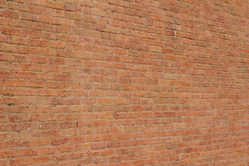 Old reddish orange brick wall background with cracks and worn texture (angle view)