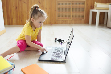 Cute girl online at the laptop. The child sits on the Internet.