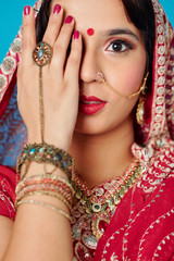 Beautiful Indian woman covering her face with hand with many bracelets and big ring and looking at camera