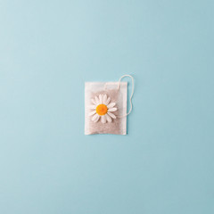 Herbal alternative medicine series: Chamomile flowers and teabags on blue background. Seasonal anti-depression, stomach and colds remedy treatment