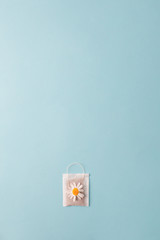 Herbal alternative medicine series: Chamomile flowers and teabags on blue background. Seasonal anti-depression, stomach and colds remedy treatment, creative lay out